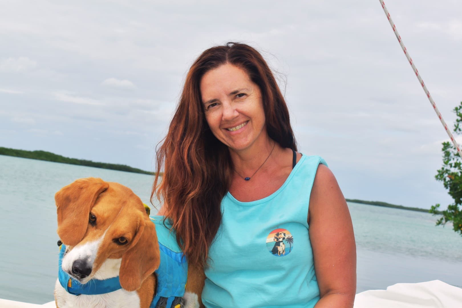 Ellie Hansen, co-founder of Marlin Sites, sitting on a sailboat on the ocean with her beagle Cedric.